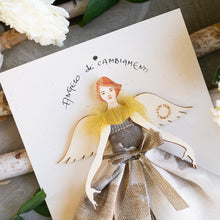Carica l'immagine nel visualizzatore di Gallery, Angelo di legno di pioppo dipinto e vestito a mano, abito in jacquard con fantasia geometrica color antracite e grigio, corpetto e maniche velati, borsetta in tessuto. Angelo dei CAMBIAMENTI Regalo ARTIGIANALE culturale e poetico, calligrafia. Packaging per un regalo perfetto o un pensiero del cuore. Fatto a mano in Italia.