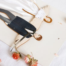 Load image into Gallery viewer, Dettaglio dell'ANGELO degli SPOSI, struttura stampata su legno e dettagli dipinti a mano, abito in raso e pizzo di cotone bianco, fiocco in lurex per la sposa, papillon nero in raso per lo sposo.