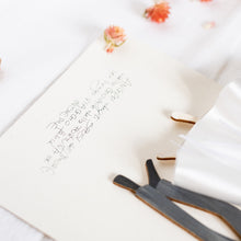Load image into Gallery viewer, Dettaglio dell'ANGELO degli SPOSI, struttura stampata su legno e dettagli dipinti a mano, abito in raso e pizzo di cotone bianco, fiocco in lurex per la sposa, papillon nero in raso per lo sposo.