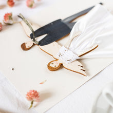 Load image into Gallery viewer, Dettaglio dell'ANGELO degli SPOSI, struttura stampata su legno e dettagli dipinti a mano, abito in raso e pizzo di cotone bianco, fiocco in lurex per la sposa, papillon nero in raso per lo sposo.