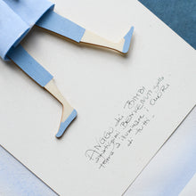 Load image into Gallery viewer, Dettaglio dell'ANGELO dei BIMBI, struttura in legno dipinta e vestita a mano, abito in cotone azzurro a pois e fiocco in raso; piccolo accessorio a forma di cavallo in legno con fiocco in raso azzurro.