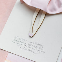 Carica l'immagine nel visualizzatore di Gallery, Dettaglio dell'ANGELO della BIMBA GRANDE, struttura in legno di pioppo dipinta e vestita a mano, abito in cotone rosa a poi e fiocco in raso; piccolo accessorio in legno a forma di agnello.