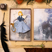 Carica l'immagine nel visualizzatore di Gallery, Angelo della ROSA dei VENTI in legno di pioppo, dipinto e vestito a mano, sottogonna di tulle, gonna di cotonina stampata, lana antracite, top di raso azzurro. Ricchissimo di accessori.