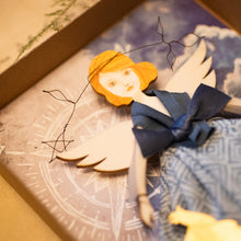 Carica l'immagine nel visualizzatore di Gallery, Dettaglio dell'Angelo della ROSA dei VENTI in legno di pioppo, dipinto e vestito a mano, sottogonna di tulle, gonna di cotonina stampata, lana antracite, top di raso azzurro. Ricchissimo di accessori.