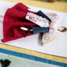 Carica l&#39;immagine nel visualizzatore di Gallery, Dettaglio dell&#39;ANGELO dell&#39;AMICIZIA, struttura in legno dipinta e vestita a mano, abito in tessuto color rosso con sottogonna in tulle bianco, top in lana color grigio e sciarpa in tessuto a fantasia floreale bianca e rossa; borsetta sagomata in tessuto rosso e piccolo fiocco di raso rosso sulla scarpetta.

