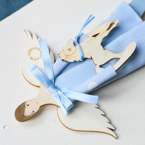 Dettaglio dell'ANGELO dei BIMBI, struttura in legno dipinta e vestita a mano, abito in cotone azzurro a pois e fiocco in raso; piccolo accessorio a forma di cavallo in legno con fiocco in raso azzurro.