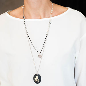Set e collana CUORE con un charm a forma di cuore lavorato, catene con perline in vetro nero e bianco perla ad incatenato, perle piatte di madreperla nera.
