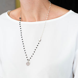 Collana CUORE con un charm a forma di cuore lavorato, catene con perline in vetro nero e bianco perla ad incatenato, perle piatte di madreperla nera.