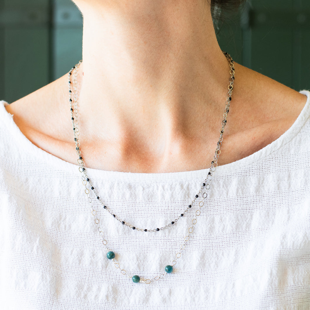 Collana DOPPIA medio-lunga a due fili, realizzata con catene color argento, perle di apatite grezzo scuro e catena a rosario con cristalli neri.