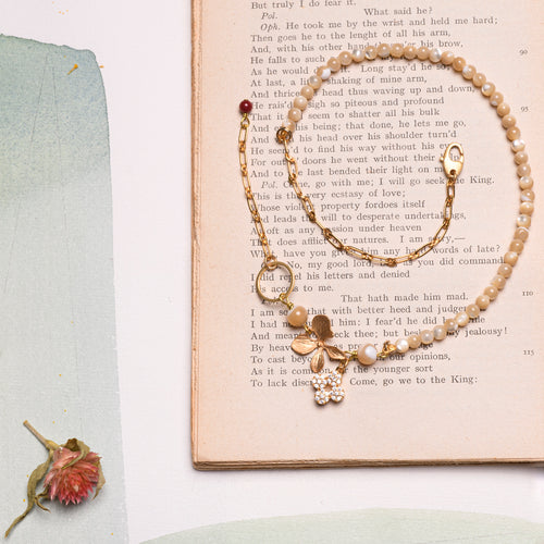 Bracciale FOGLIA e FIORE a doppio giro con un elemento metallico a forma di foglia, charm pendente a forma di fiore con zirconi incastonati e perline di madreperla cappuccino.