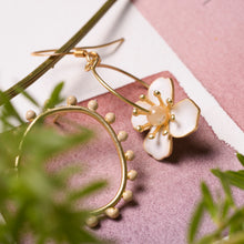Load image into Gallery viewer, Dettaglio degli orecchini FIORE asimmetrici con un elemento metallico a coroncina smaltato ed uno a cerchio con fiore smaltato e perlina in madreperla cappuccino.
