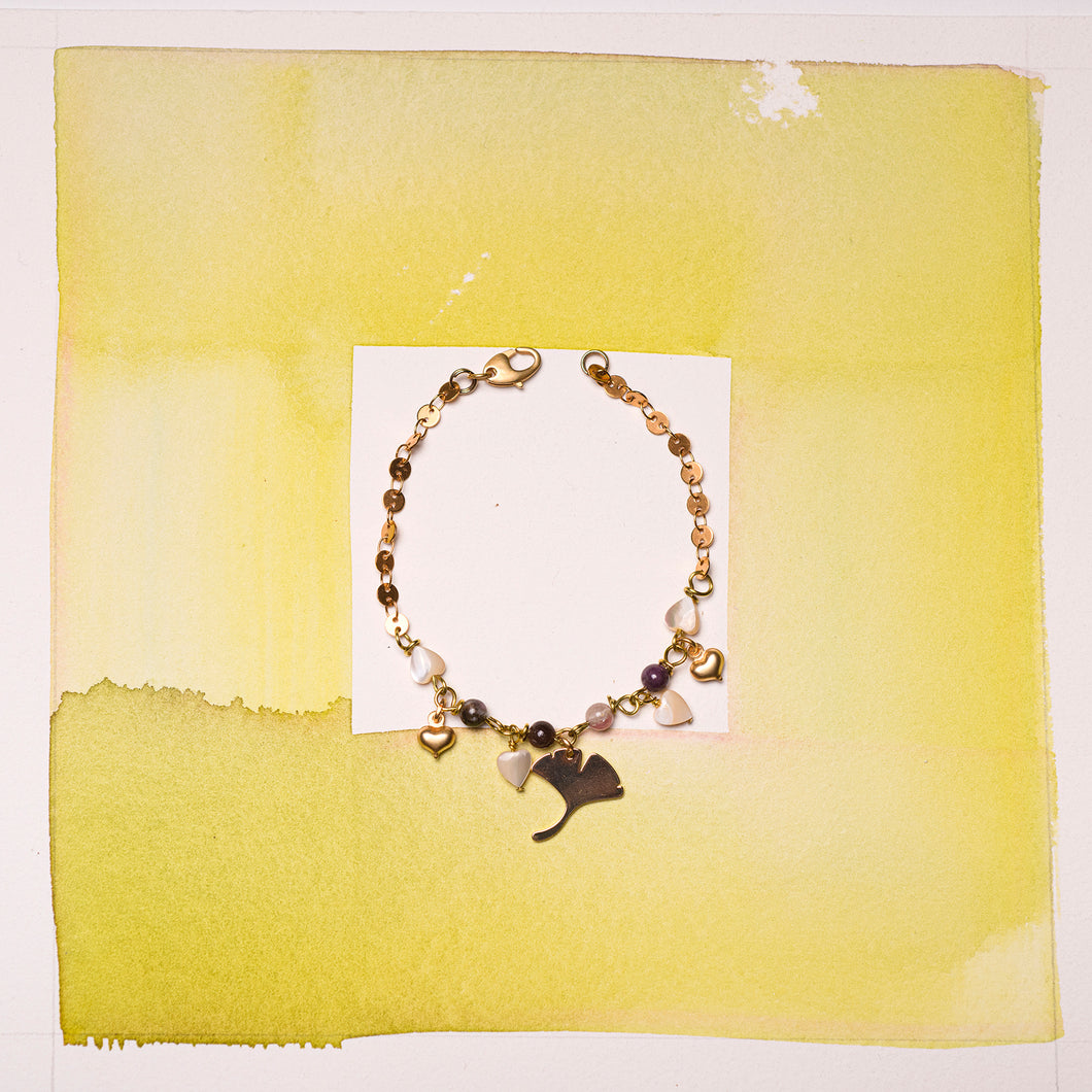 Bracciale GINGKO con una particolare catena a dischetti, sferette in tormalina multicolor e cuoricini in madreperla cappuccino; charms pendenti in metallo dorato a forma di cuori e gingko. 
